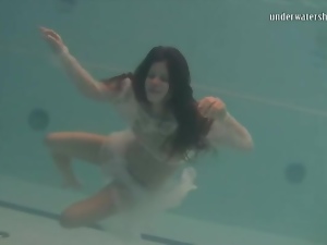 Young brunette swims in sheer white clothes